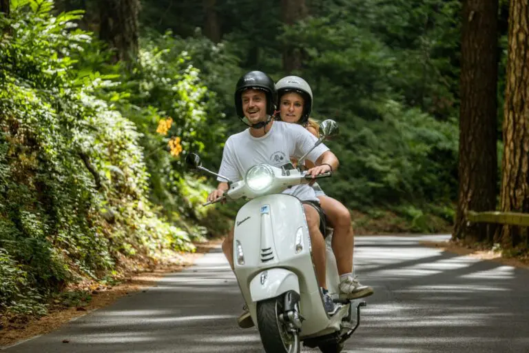 couple driving a Vespa in Amalfi during Vespa trip Koppel dat Vespa rijdt in Amalfi tijdens Vespa trip